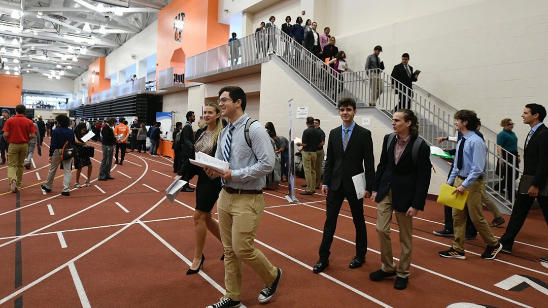 Students dressed in professional attire with resumes in hand enter Gordon Field House. 