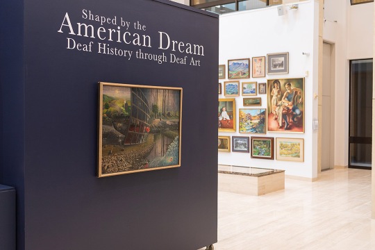 Entrance to Dyer Arts Center has sign that says "Shaped by the American Dream Deaf History through Deaf Art." Works of art are shown on wall.