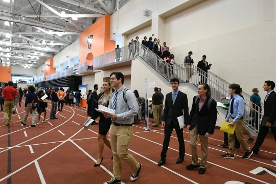 Students dressed in professional attire with resumes in hand enter Gordon Field House. 