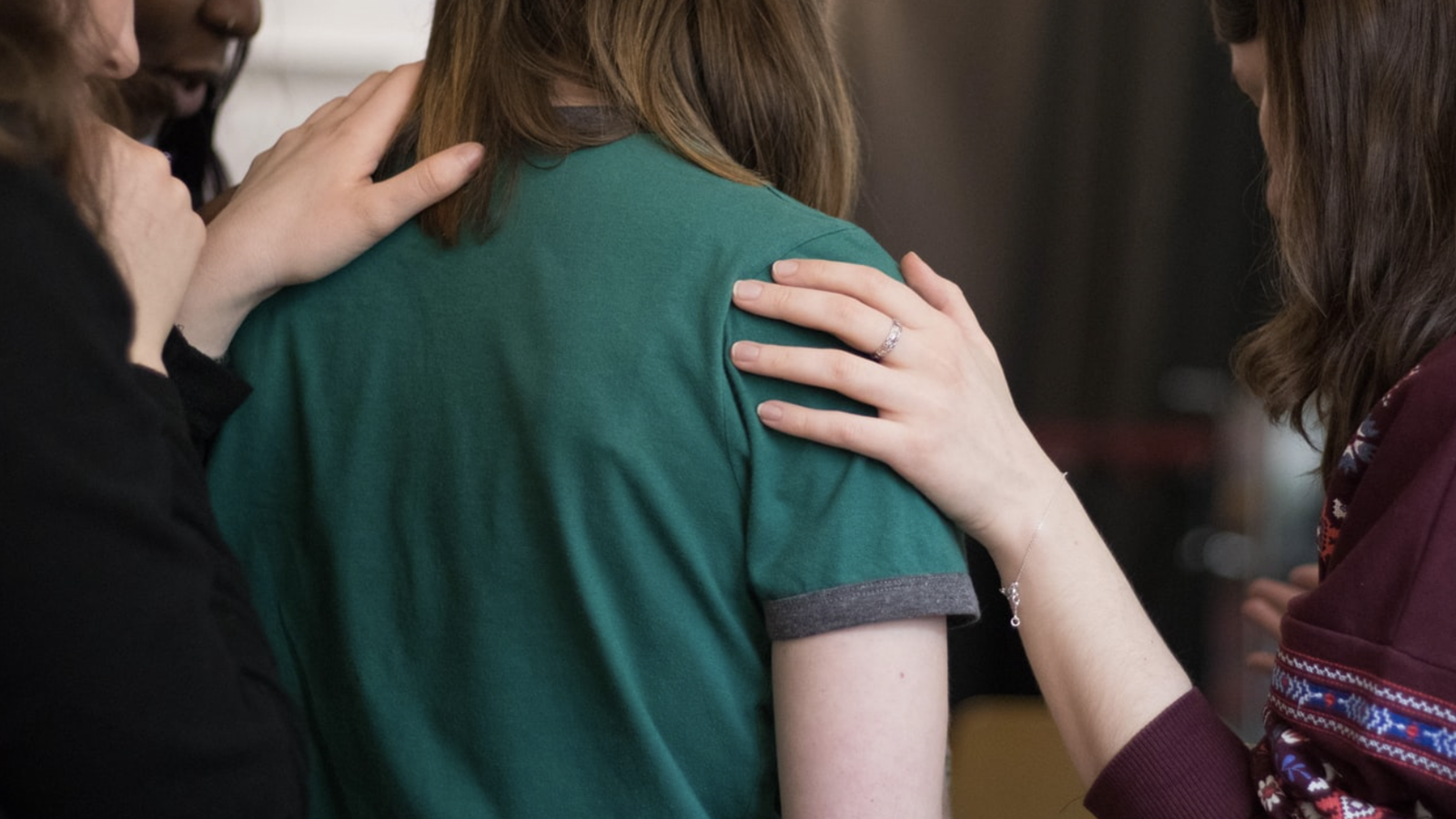 A woman in green shirt being comforted by friends