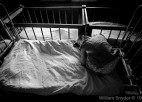 A young girl is tied to a bed.