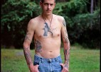 A portrait of a shirtless man with tattoos.