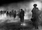 A group of people walk through a smoky area.
