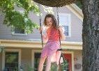 A girl swings from a swing hanging from a tree.