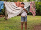 A person poses while standing next to a clothesline.