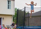 A child bounces on a trampoline as parents look on.