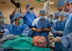 Surgeons gather around a patient in an operating room.