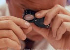 A man inspects a very small object.