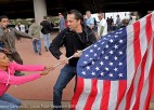 A man attempts to rip an American flag out of the hands of a woman.