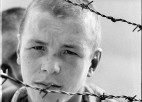 A photo of a boy behind barbed wire.