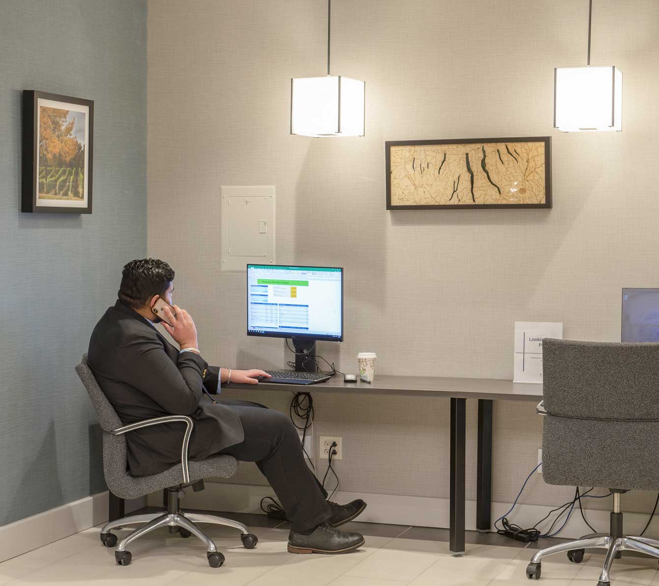 Man in suit sitting in a chair on the phone using a computer