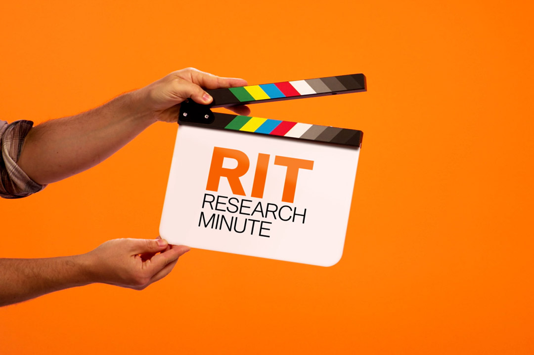 hands hold a directors cut board that says RIT Research Minute