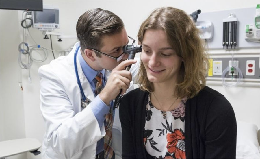 a doctor looking at a patience ear in a medical room