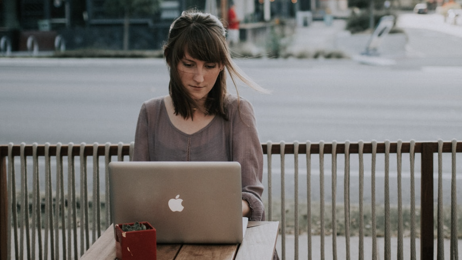 Woman in grey shirt using Mac laptop at a coffee shop