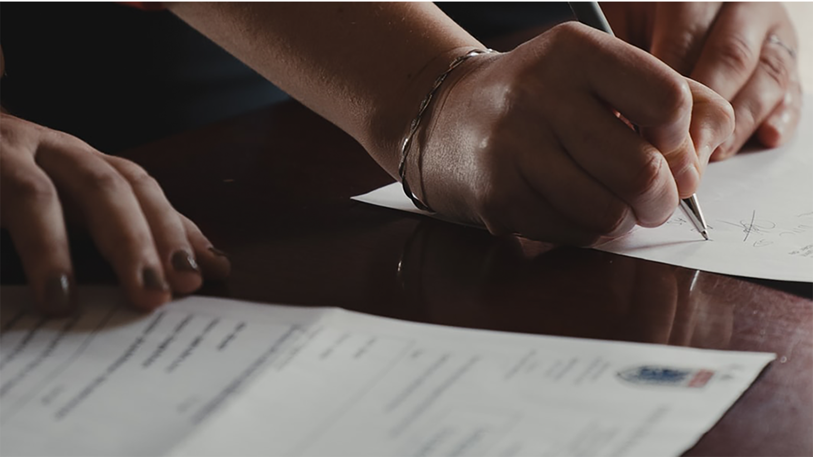 Someone signing some paperwork on a table