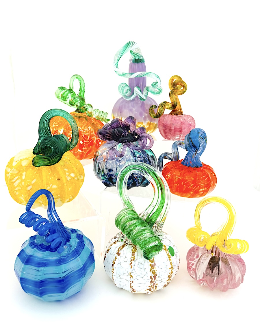 a group of nine glass pumpkins in a variety of shapes and colors.