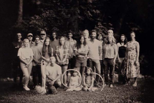 Black and white photo of a group of people posing for a photo outside in grass