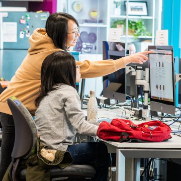 Two people looking at a computer and one pointing at the screen