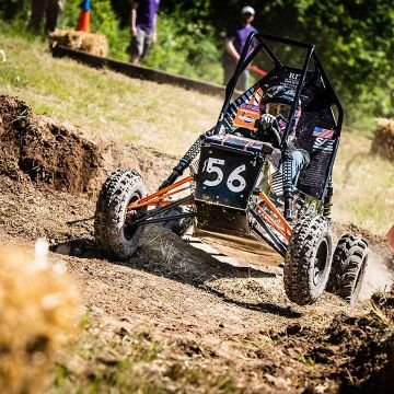 A baja racecar driving through a mud track