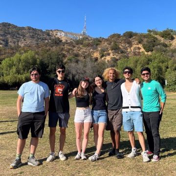 A group of people standing arm in arm outside in a field