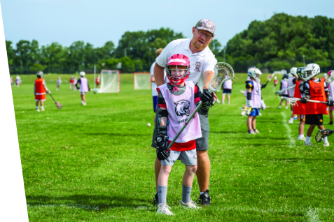 A coach showing a kid how to hold a lacrosse stick