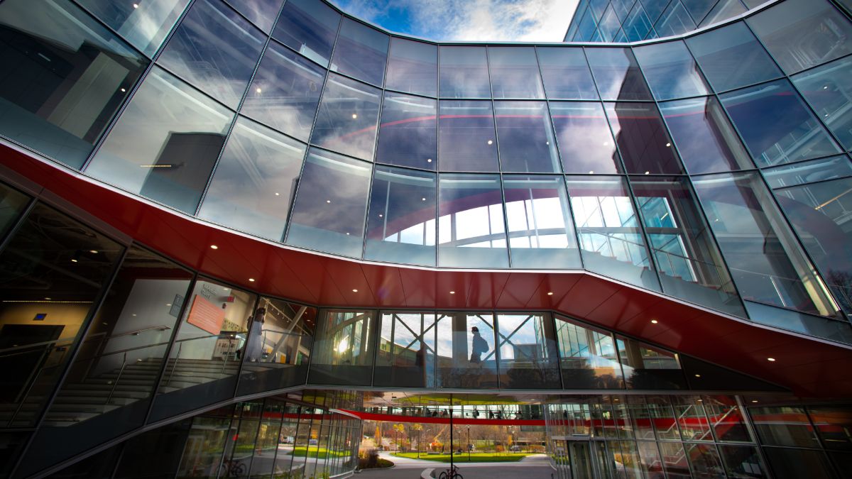 The interior view of a building with large curved glass windows reflecting the sky.