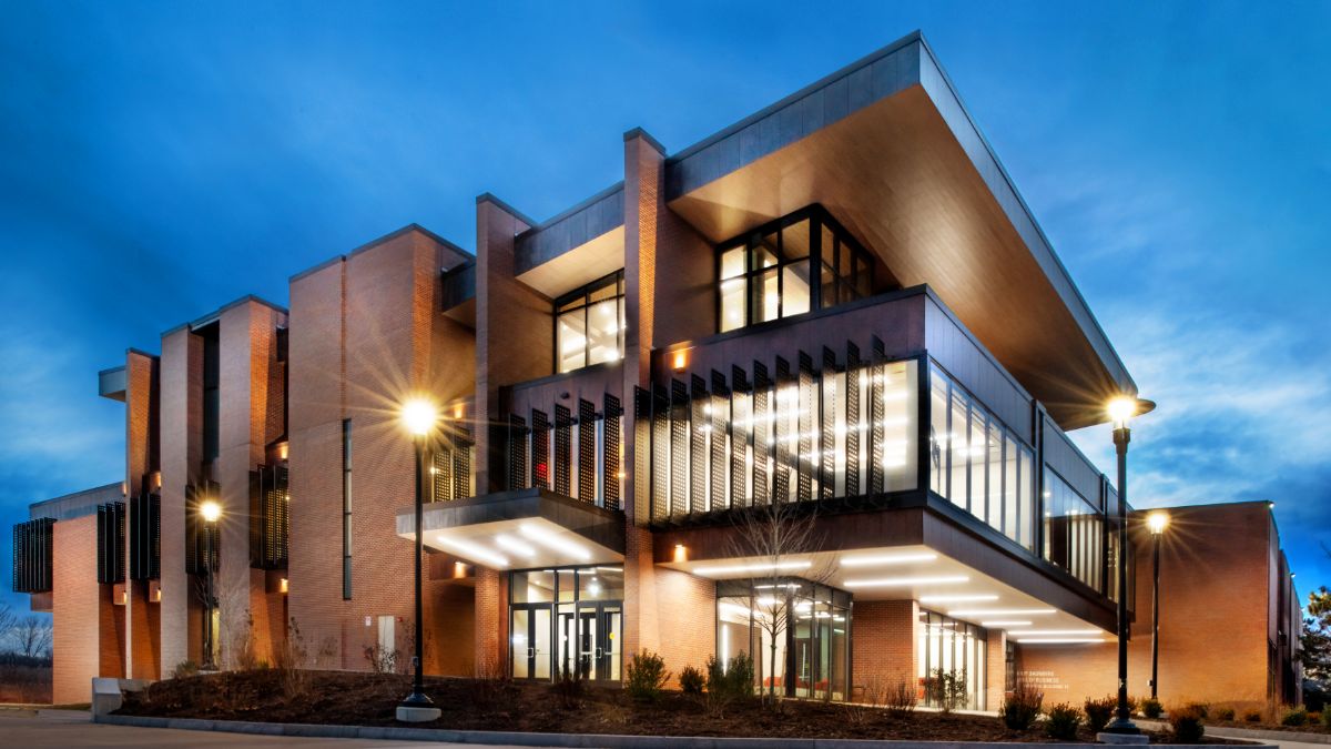 Illuminated brick academic building with large glass windows glowing at night.