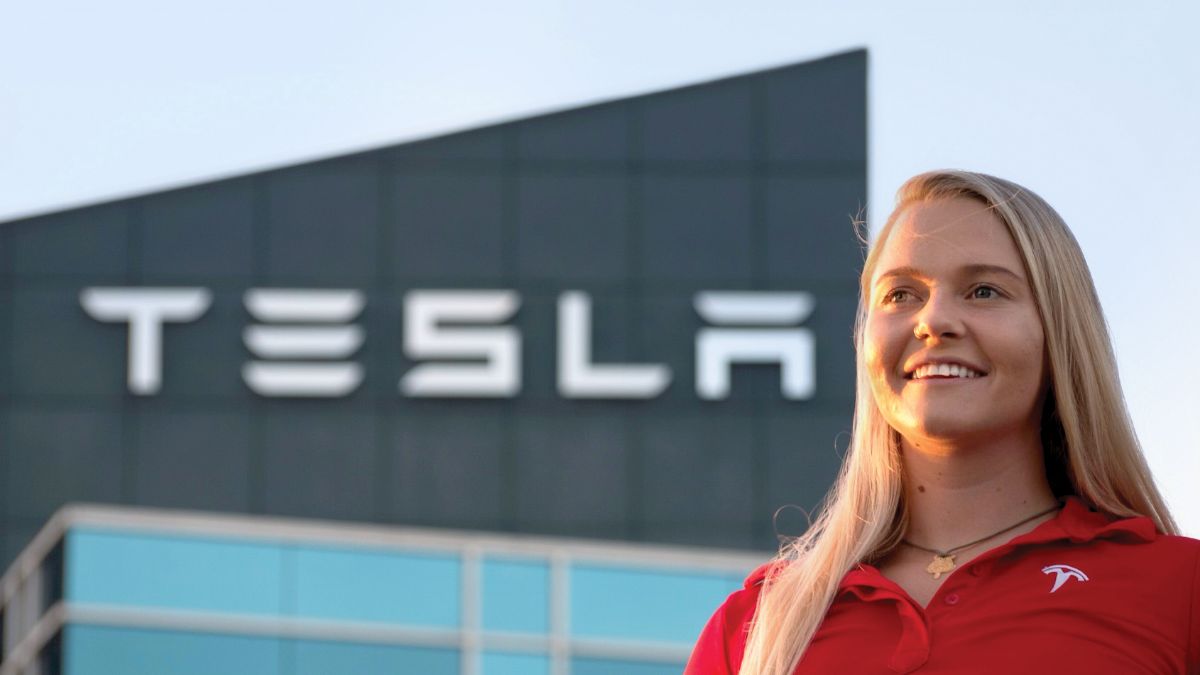 woman posing outside of a Tesla building.