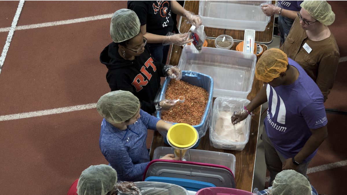 students packaging ingredients for a food donation in an assembly line.