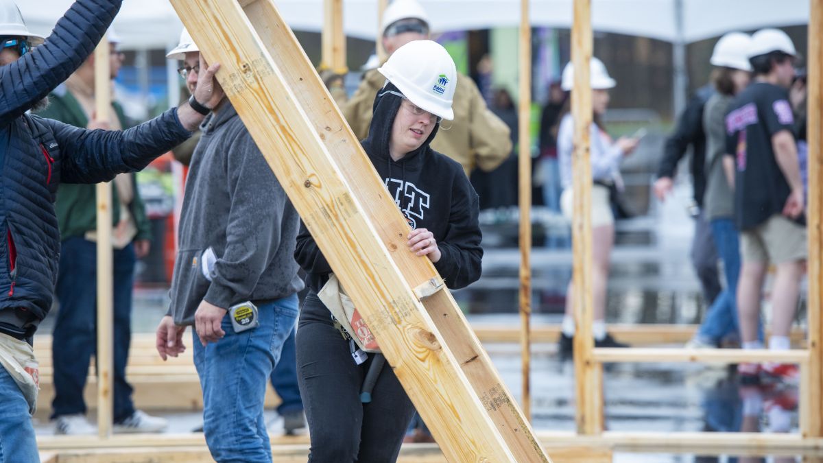 Students lifting construction beams while working on a community housing project.