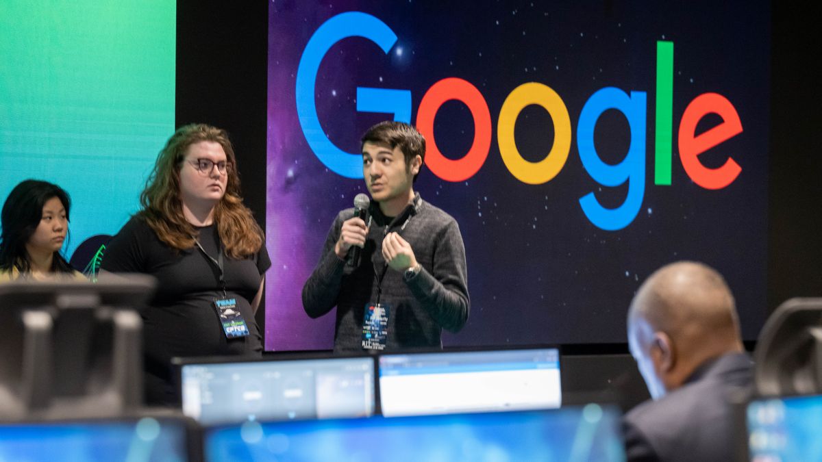 Students giving a presentation in front of a sign for Google.