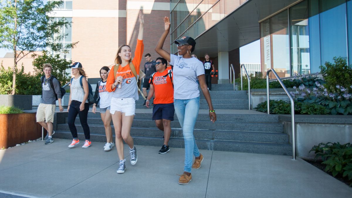 two students high-fiving outside on a sunny day.