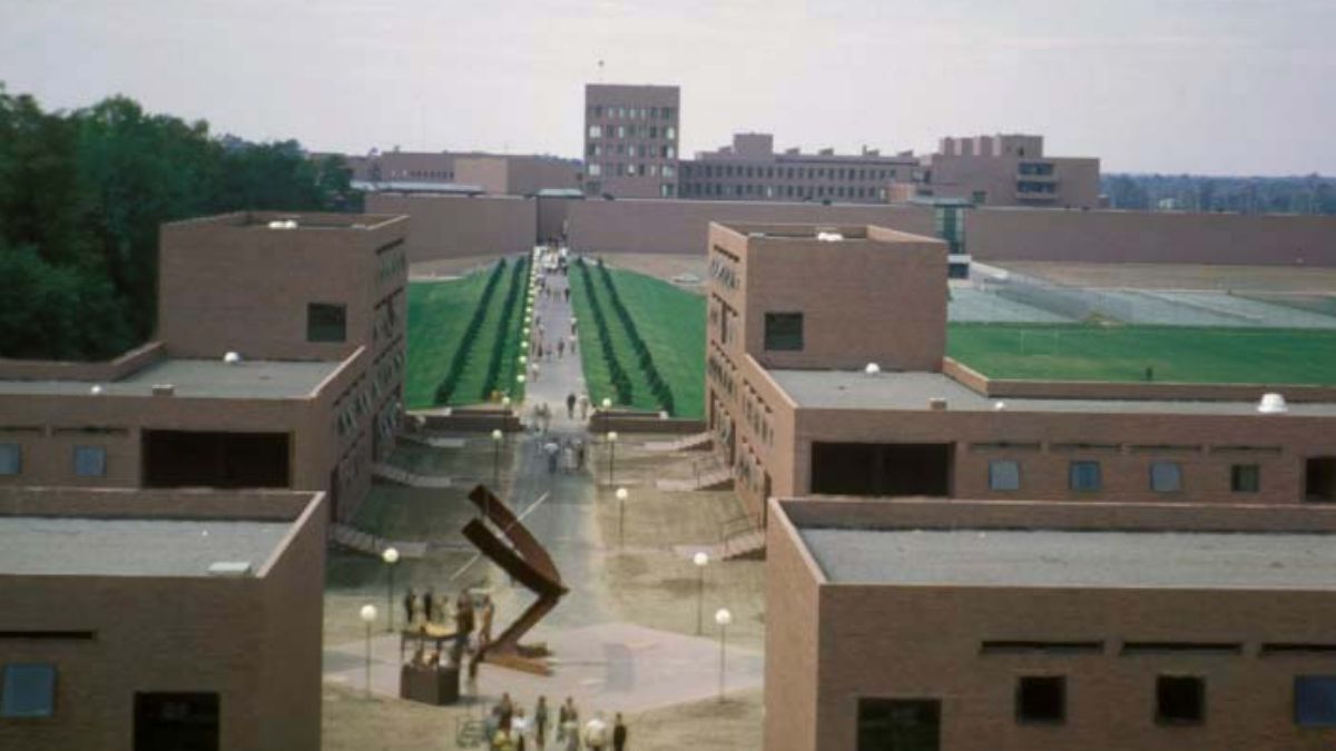 A historical aerial view of the modern RIT campus, showcasing brick buildings and green pathways.