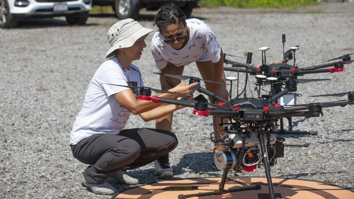 Two individuals inspecting a large drone closely during a field test.