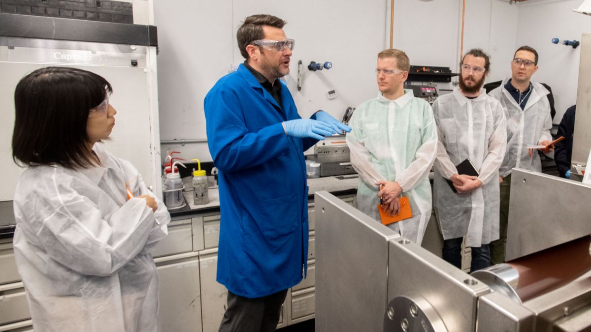 A research group listens attentively to a presentation in a laboratory setting.