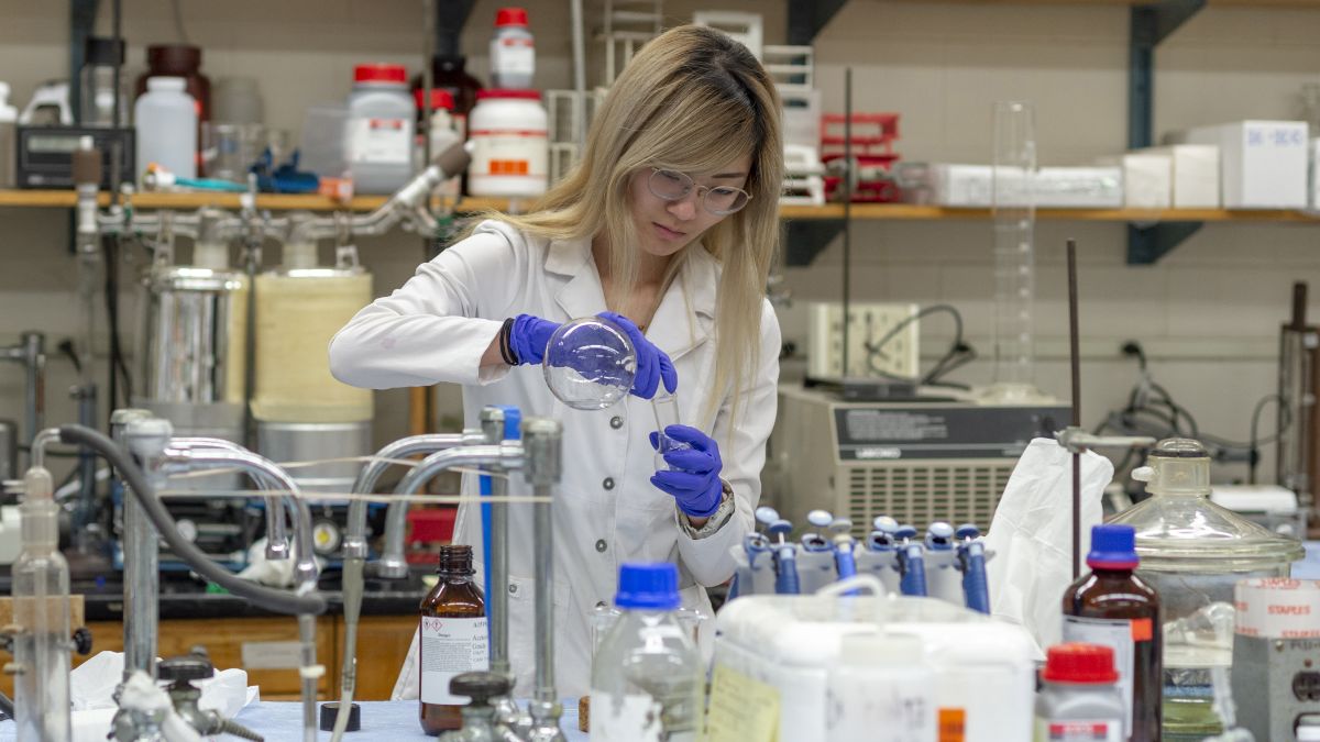 A scientist working in a laboratory, carefully pouring chemicals into a flask.