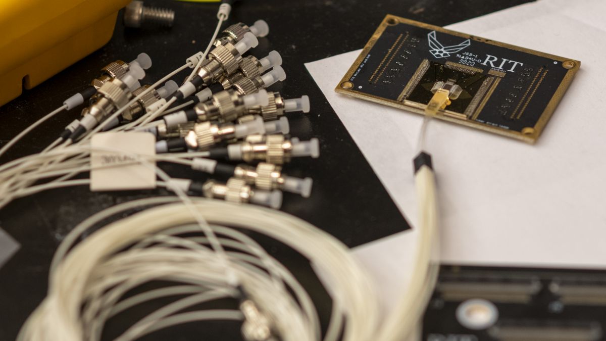 A close-up of research equipment with cables and sensors connected to a circuit board labeled R I T.