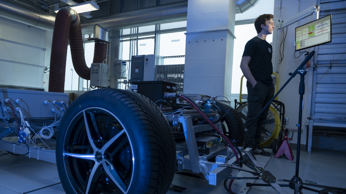 a car chassis in a test lab, with a researcher looking at data on a computer screen.