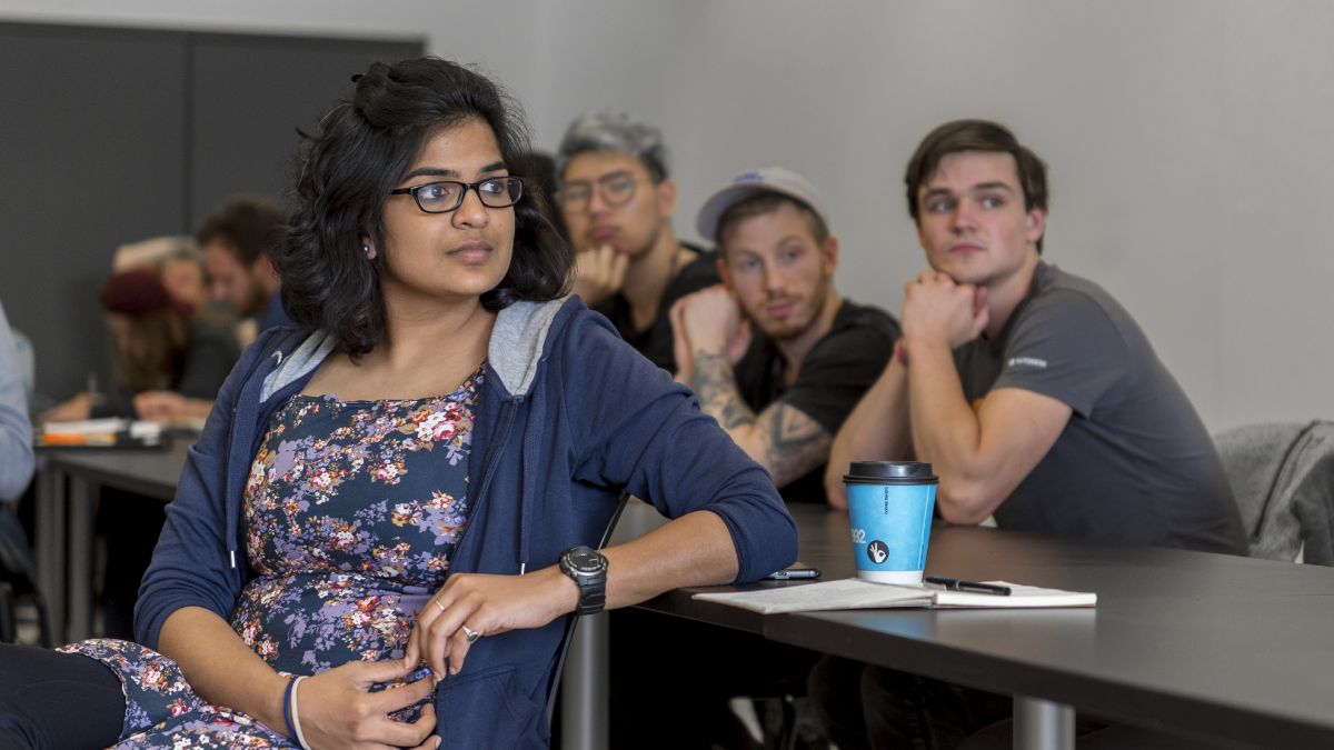 A group of students in a classroom, some listening attentively.