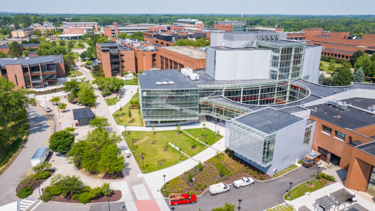 Aerial view of the RIT campus featuring modern buildings and green spaces under a bright sky.