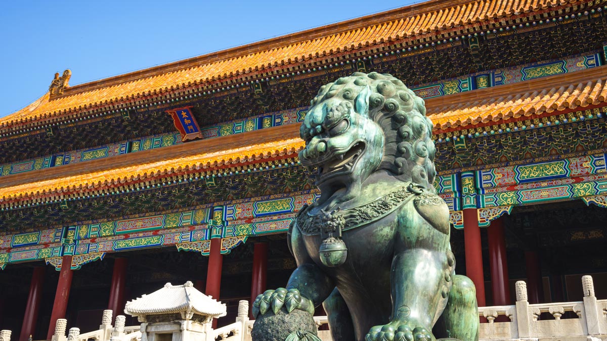 Ornamental Chinese building with lion statue in front of it.