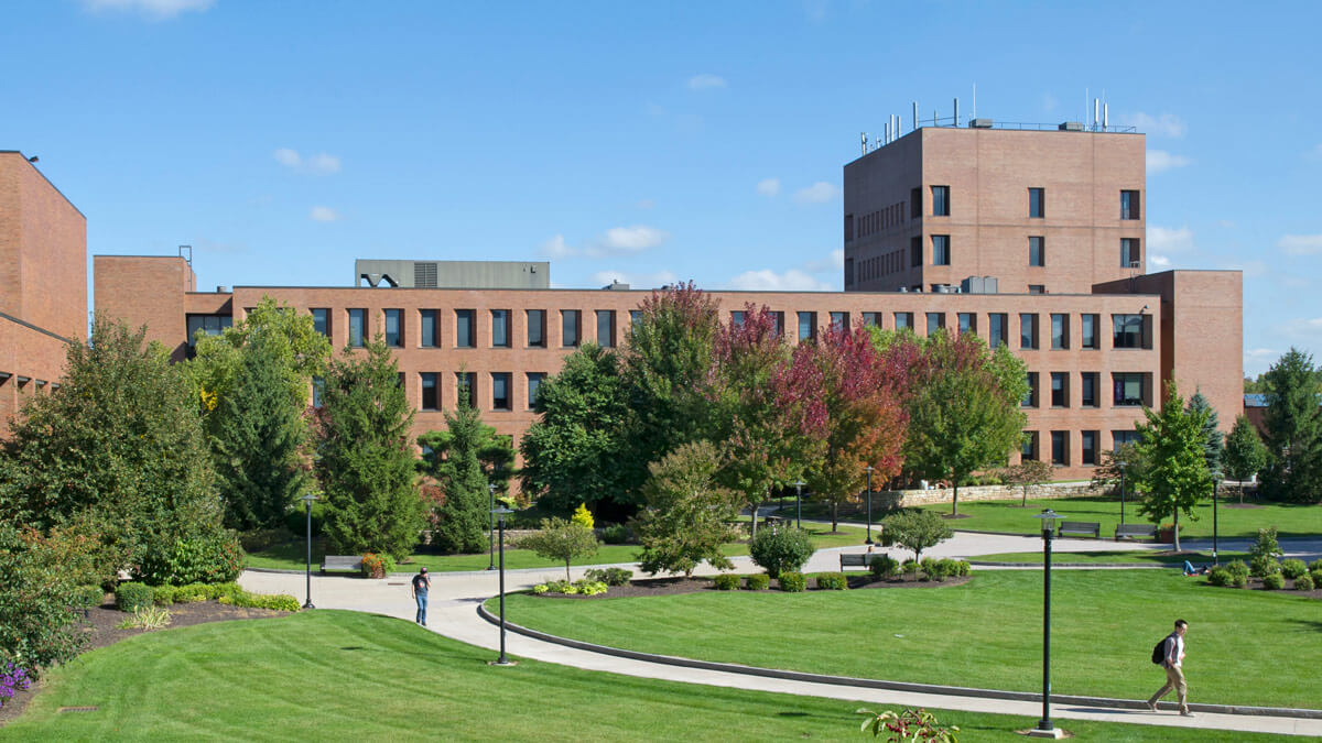 View of RIT campus with several trees and bushes in front of a brick building.