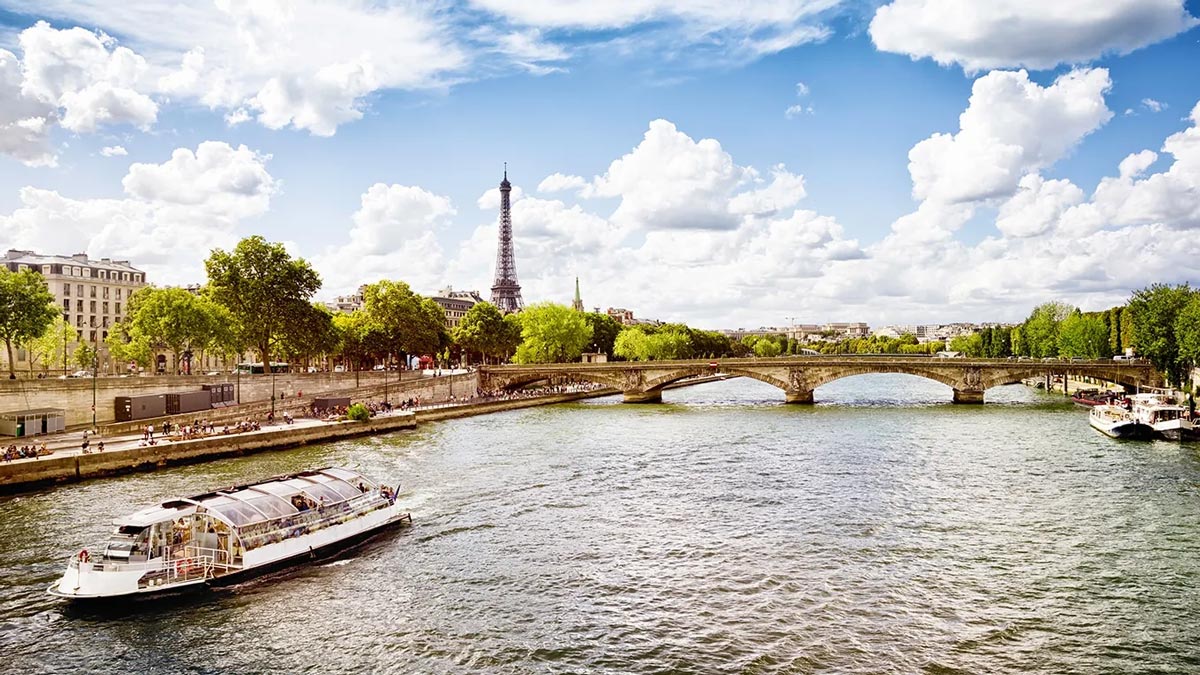 Landscape photo over a river with the Eiffel Tower in the background.