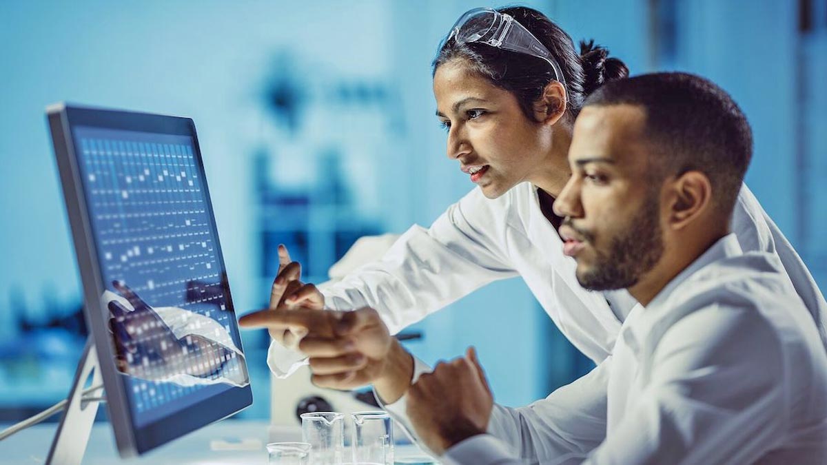 Two people looking at a computer screen with charts.