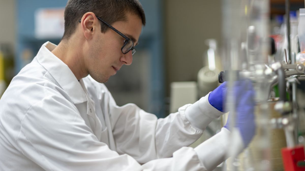 Student looking at a vial in a lab.