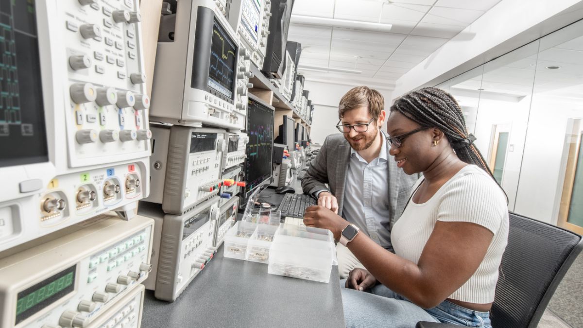 A student and professor working with wires and a bread board.