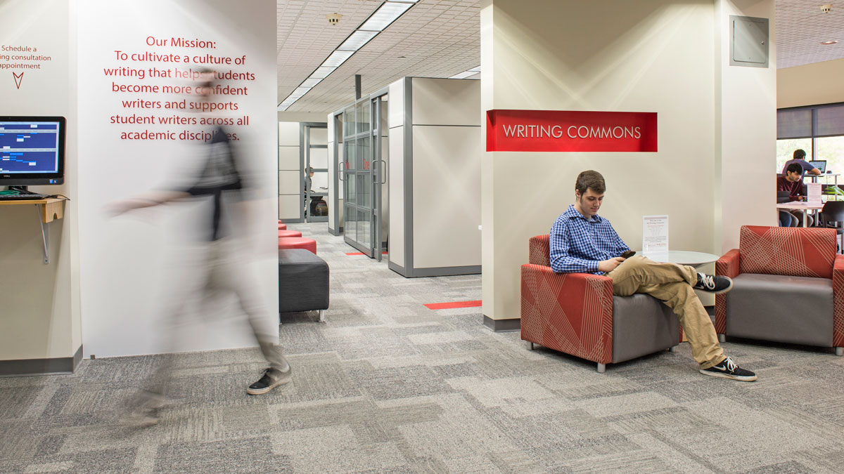 Student sits in a chair under a Writing Commons sign.