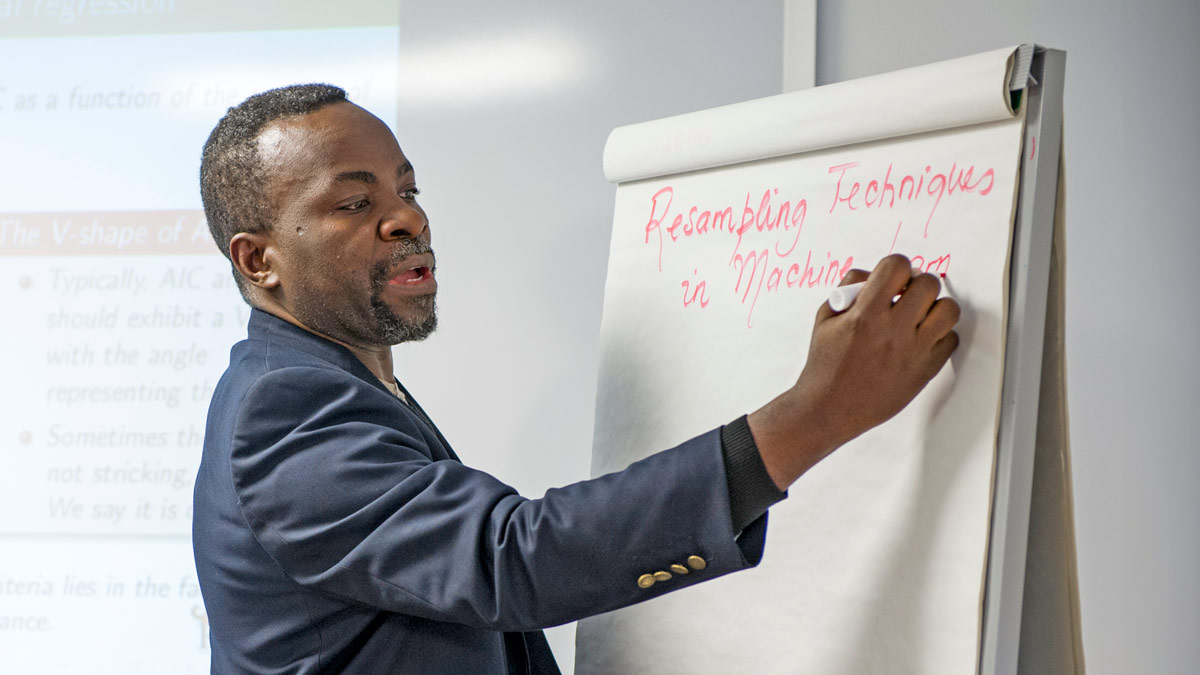 A teacher writes on a large, standing notepad.