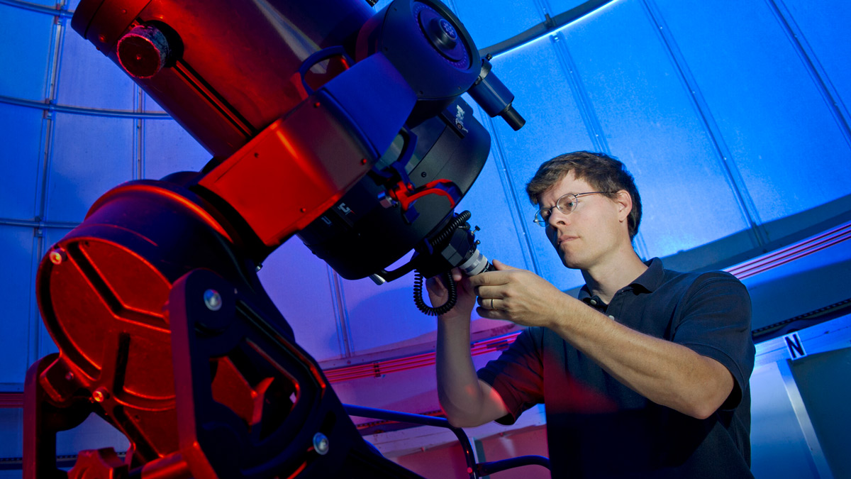 Man working on a large telescope.