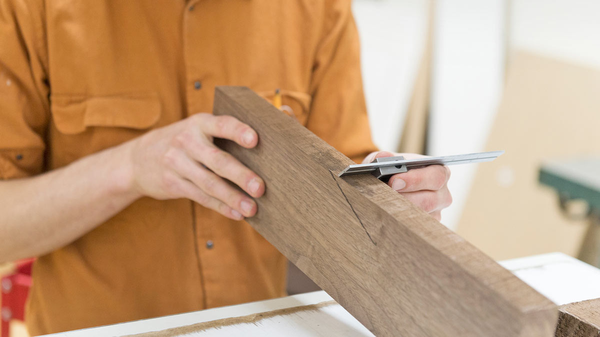 Close up of hands measure a piece of wood.